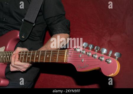 Vaduz, Liechtenstein, 11 gennaio 2022 il musicista suona un Fender Stratocaster USA realizzato 1995 nel colore della nebbia di borgogna Foto Stock