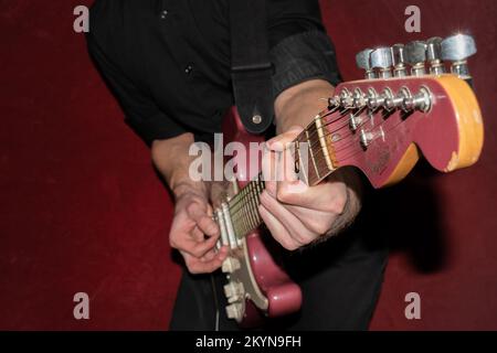 Vaduz, Liechtenstein, 11 gennaio 2022 il musicista suona un Fender Stratocaster USA realizzato 1995 nel colore della nebbia di borgogna Foto Stock