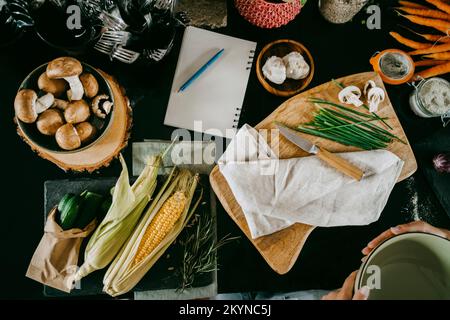 Direttamente sopra la vista di verdure fresche e diario tenuto sul banco in studio Foto Stock