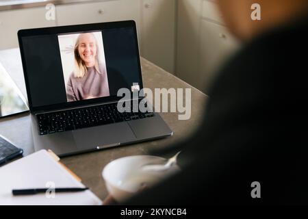 Donna d'affari che parla con l'uomo d'affari attraverso la videochiamata sul laptop a casa Foto Stock