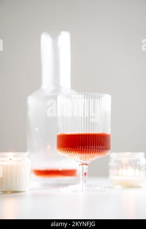 Vino rosato in vitelle alla moda e decanter su tavola bianca Foto Stock