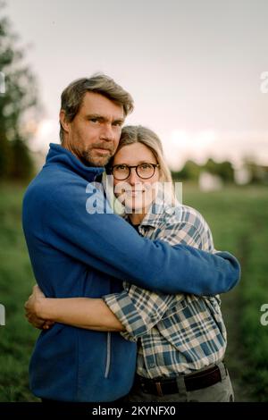Coppia felice che si abbraccia sul campo durante il tramonto Foto Stock