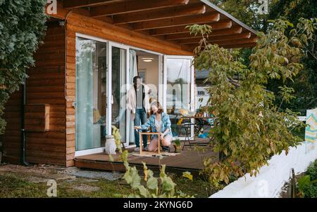 Uomo e donna aiutandosi mentre dipingendo mobili sul portico Foto Stock