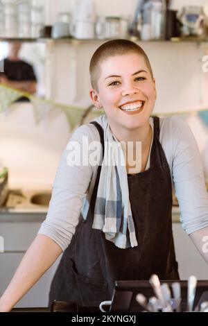 Ritratto di felice padrona di casa che indossa grembiule in caffè Foto Stock