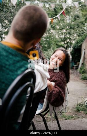 Donna sorridente che guarda l'amico femminile durante la festa a cena nel cortile posteriore Foto Stock