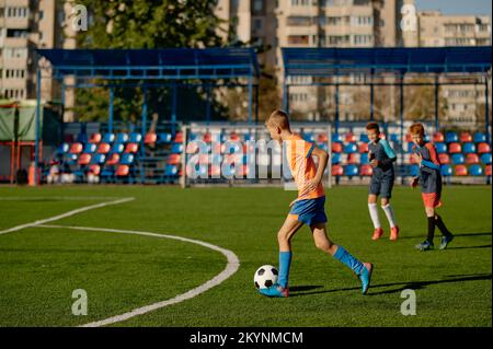 Ragazzi giovani che giocano a calcio partita al campo di allenamento per bambini Foto Stock