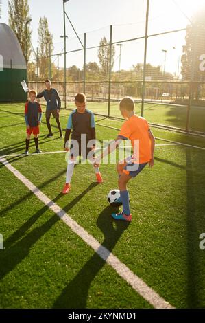 Ragazzi giovani che giocano a calcio partita al campo di allenamento per bambini Foto Stock