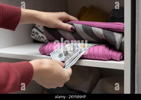 l'uomo nasconde i soldi in un armadio con i vestiti Foto Stock