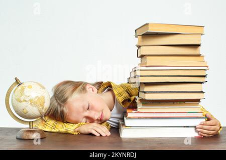 Concetto di istruzione. Lo studente si addormentò mentre faceva i compiti. Vicino a libri e un globo Foto Stock