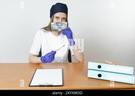 Medicina e concetto di salute. Giovane medico dentista femminile esamina un'istantanea della mascella. Isolato su sfondo bianco. Foto Stock