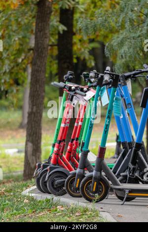 Kharkiv, Ucraina - 5 ottobre 2021: Noleggio scooter elettrici in piedi in autunno parco della città. E-scooters pubblico, popolare mezzi di trasporto moderni Foto Stock