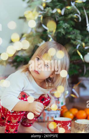 Affascinante bambino che gioca vicino all'albero di natale Foto Stock