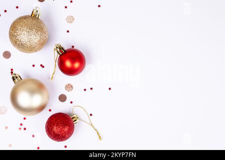 Sfondo bianco di natale con palle dorate e rosse, coriandoli rotondi e stellari, vista dall'alto piatta con spazio copia. Modello per cartoline e banner . Foto Stock