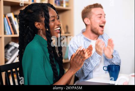 Amici biraciali che si divertono in biblioteca dopo aver studiato per gli esami universitari Foto Stock