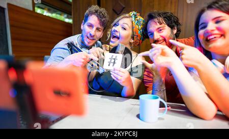 Gruppo di amici che conducono programmi radiofonici in streaming dal vivo e ricordano ai loro fan di seguirli sui social media Foto Stock