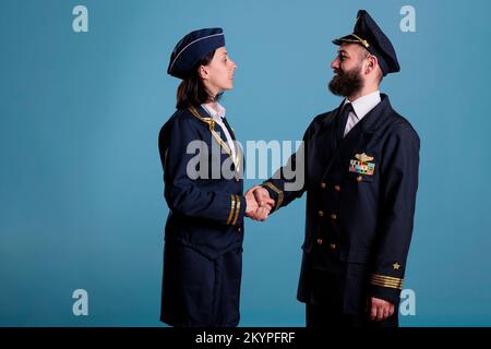 Pilota sorridente di aeroplano e assistente di volo che scuote le mani ritratto, equipaggio di aeroplano in handshake professionale uniforme. Saluto del capitano e della hostess dell'aereo, collaborazione dell'equipaggio Foto Stock