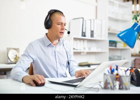 Operatore telefonico con cuffie durante il lavoro nel call center Foto Stock