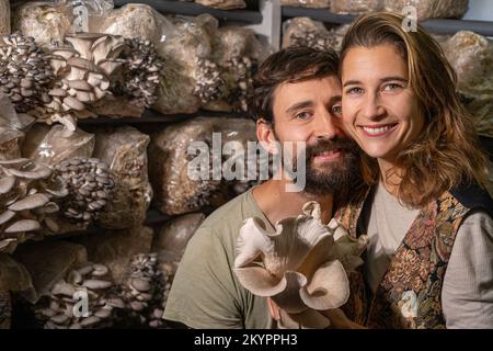 felice coppia contadina che tiene funghi ostriche in fattoria funghi Foto Stock