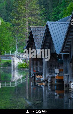Al mattino presto nel villaggio di Obertraun, con vista sulle barche del lago ormeggiate in scivoli coperti Foto Stock