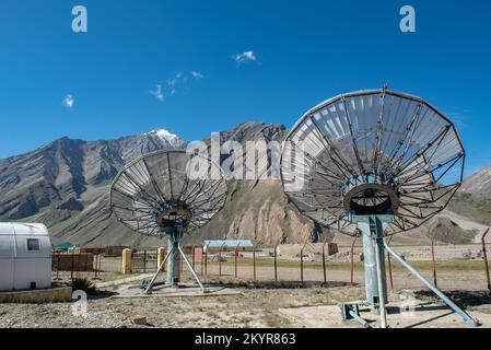 Comunicazione satellitare piatti rete tecnologia in zona rurale con la gamma di montagna e cielo blu sfondo. Foto Stock