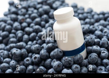 Flacone con medicinale sullo sfondo di un grande mirtillo Foto Stock