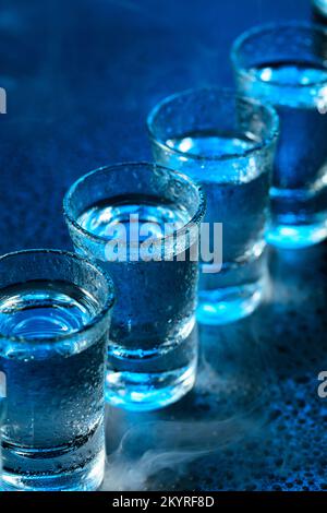 Bicchieri bagnati di vodka in fumo su sfondo blu scuro. Messa a fuoco selettiva. Foto Stock