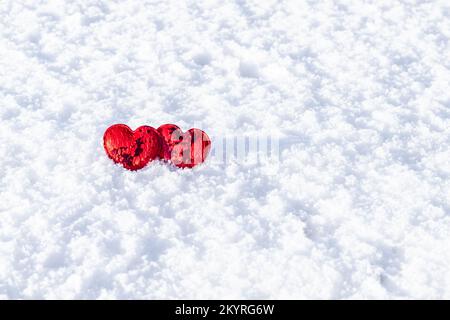 Due cuori rossi su uno sfondo di neve bianca. Luogo per un'iscrizione. CopySpace. San Valentino. Foto Stock