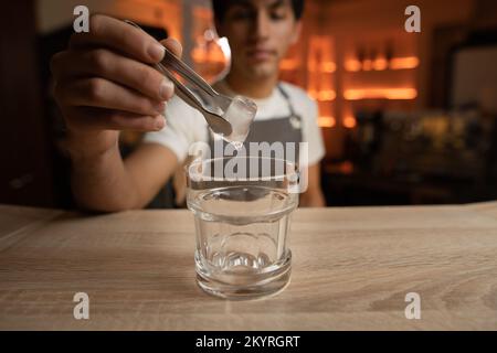 Barman al banco. L'uomo tiene un bicchiere di champagne. Uomo con il  portatore sicuro in abito nero al bar. Bevanda alcolica Foto stock - Alamy