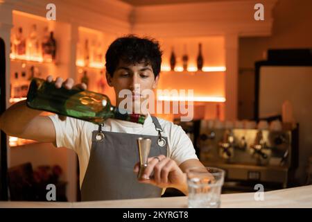 Barman in grembiule aggiunge l'ingrediente al vetro Foto stock - Alamy