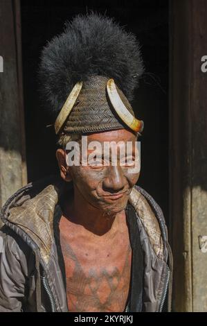 Mon, Nagaland, India - 11 25 2013 : Ritratto della vecchia tribù Naga cacciatore capo guerriero con il tradizionale viso e petto tatuaggio indossare cappello Konyak Foto Stock