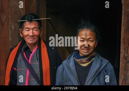 Ziro, Arunachal Pradesh, India - 03 05 2014 : sciamano tradizionale vecchio Apatani tribale e moglie in piedi fuori della loro casa di villaggio Foto Stock