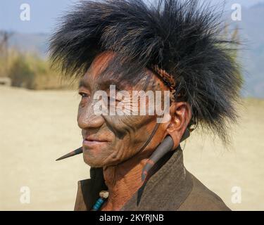 Mon, Nagaland, India - 03 10 2014 : Ritratto in primo piano della vecchia tribù Naga Konyak cacciatore di testa guerriero con tatuaggio facciale, cappello di pelliccia e orecchini a corno Foto Stock