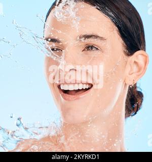 Viso, donna e acqua per la cura della pelle, bellezza naturale e viso organico su sfondo blu studio. Gocce giovani femminili, femminili e liquide per l'igiene Foto Stock