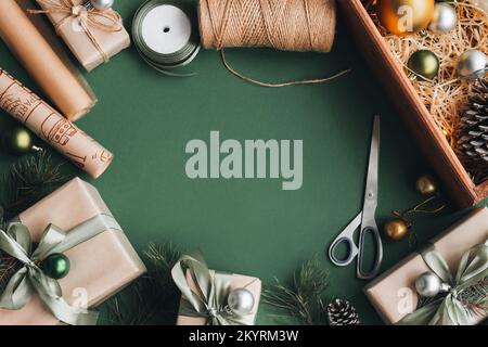 Hobby creativo. Le mani della donna avvolgono le feste di natale regalo fatto a mano in carta artigianale con nastro di spago. Fare l'arco alla scatola regalo di natale, decorata con sn Foto Stock