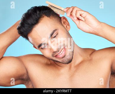 Cura dei capelli, bellezza e uomo spazzolando i capelli, marketing barbiere e salone di cura su sfondo blu in studio. Cura di sé, cura del corpo e modella thinking Foto Stock