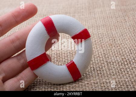 Mano che tiene un Lifesaver o conservatore di vita su uno sfondo di tessuto Foto Stock