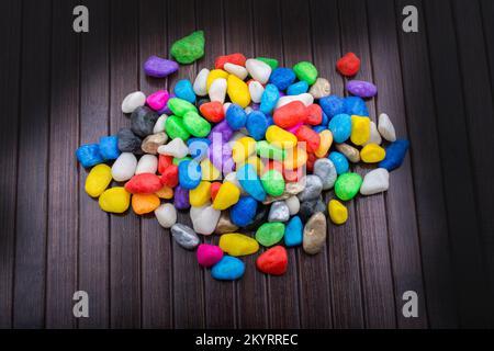 Pila di piccoli ciottoli colorati su sfondo di legno Foto Stock