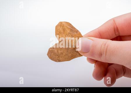 Mano che tiene una a forma di cuore ad bruciata di una carta Foto Stock