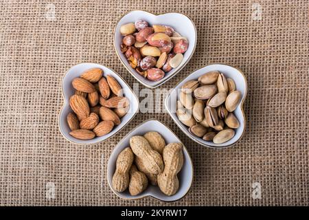 Arachidi, mandorle, pistacchio in piatti a forma di cuore su tela Foto Stock