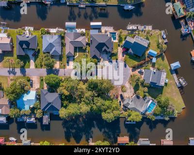 Vista aerea delle case sul lungomare lungo una baia nella comunità Navarra Florida. Case residenziali e case cittadine viste dall'alto con piccole barche ancorate Foto Stock