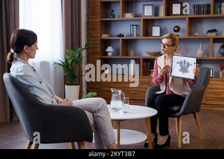 Psicologa femminile che mostra la scheda test Rorschach al paziente durante la sessione di consulenza. Esame delle caratteristiche di personalità ed emotivo Foto Stock