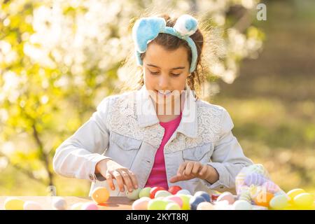 Felice ragazza teen indossare coniglietto orecchie con le uova di Pasqua in giardino Foto Stock