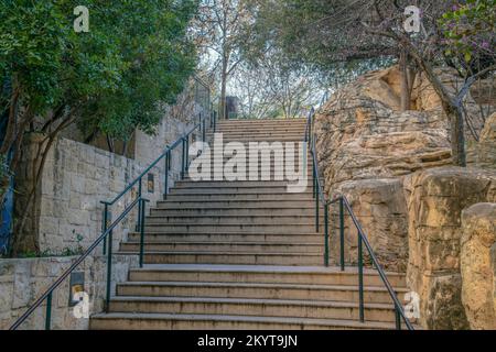 Scalinata all'aperto accanto al San Antonio River Walk in Texas in una bella giornata. La scalinata in cemento con ringhiere è fiancheggiata da mezze pareti in pietra e piccole Foto Stock