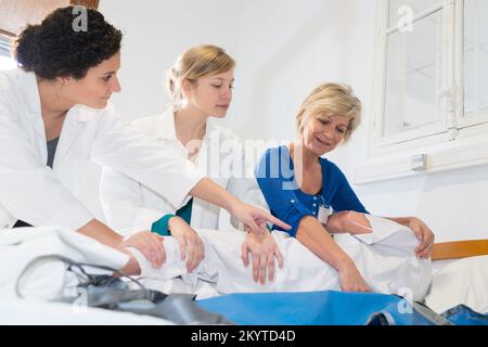 infermieri che aiutano un paziente a uscire dal letto Foto Stock