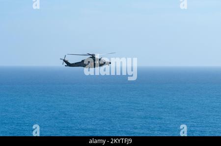 Elicottero a porta aperta che sorvola il mare visto in Italia Foto Stock