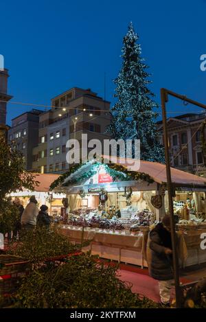 Centro città al crepuscolo con il tipico mercatino di natale, luci e grande albero di Natale. Città di Varese, piazza Monte Grappa, Italia settentrionale Foto Stock