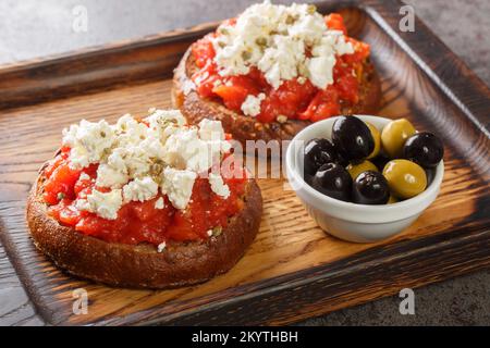 Il cretan dakos è per un'insalata tradizionale dell'isola di Creta consiste di rusk di orzo sormontato con pomodori succosi, formaggio e olio di oliva closeup su t Foto Stock