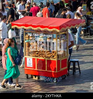 Istanbul, Turchia - 30 agosto 2022: Peddler maschile che vende simit, sul tradizionale carrello turco fast food a Eminonu Piazza Foto Stock