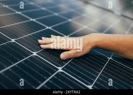 Primo piano di una mano giovane ingegnere che controlla il funzionamento del sole e la pulizia dei pannelli solari fotovoltaici. nuovo inizio. Energia rinnovabile Foto Stock