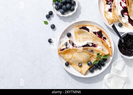 Crepes con confettura di mirtilli, ricotta e frutti di bosco freschi. Frittelle dolci per colazione. Vista dall'alto Foto Stock